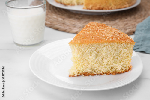 Plate with piece of tasty sponge cake on white marble table