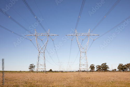Tall High-Voltage Pylons Amidst Expansive Grasslands