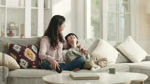 young asian mother and five-year-old son having a conversation sitting on family couch at home
