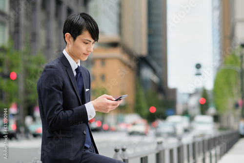 通りでスマートフォンを見るビジネスマン
