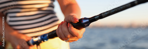 Woman holds fishing rod with reel while fishing in the sea.