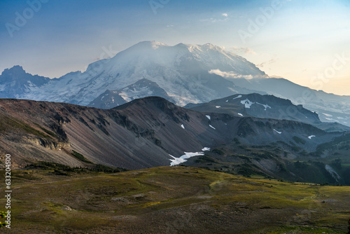 Mount Rainier  Washington in the golden hour with grassy meadow and rocky foothills in the foreground
