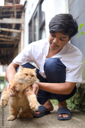 Asian guy playing with his lovely cat outdoors