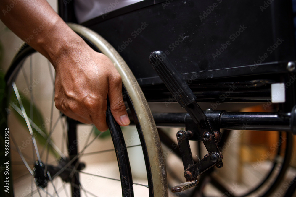 Obraz premium Unrecognizable disabled man sitting in a wheelchair. Recovery and healthcare concepts.