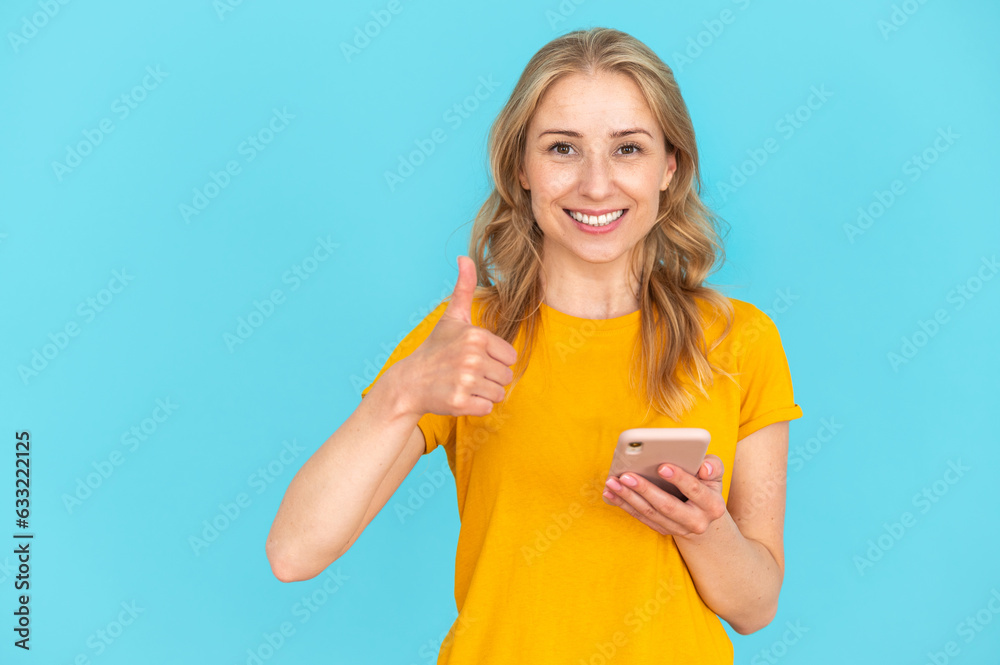 Smiling female holding smartphone and showing thumb-up, like gesture