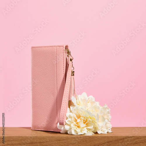 A beautiful pink wallet for money or business cards with flowers on a pink background. Copy space for text.