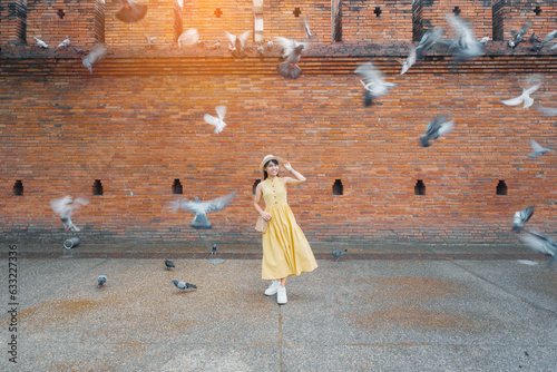 Young asian woman traveler in Yellow dress with hat and bag traveling on Tha Pae Gate, Tourist visit at the old city in Chang Mai, Thailand. Asia Travel, Vacation and summer holiday concept