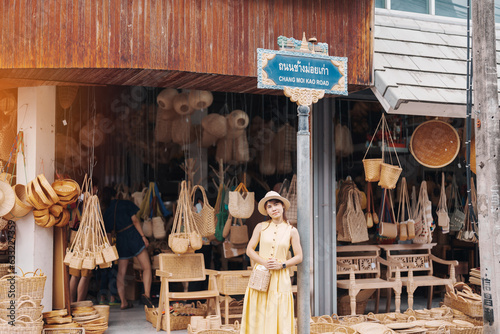 Young asian woman traveler in dress with hat traveling to wicker shop on Chang Moi Kao Road, Tourist visit at the old city in Chang Mai, Thailand. Asia Travel, Vacation and summer holiday concept photo