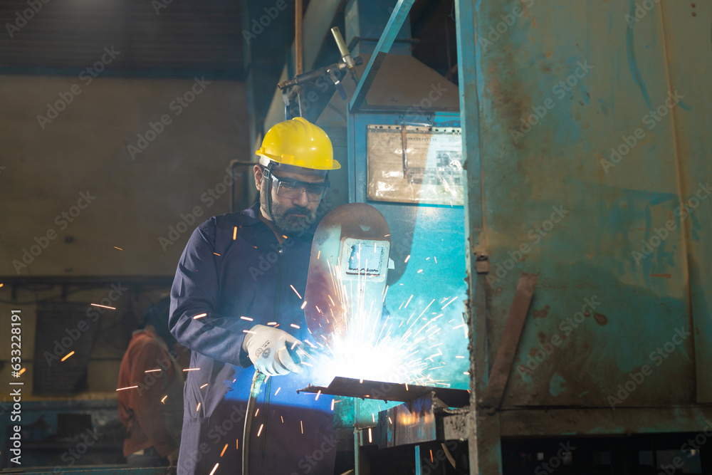 welder wearing protective hat, eyeglasses while working at factory welder wearing protective hat, eyeglasses while working at factory