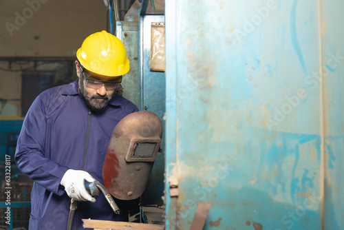 welder wearing protective hat, eyeglasses while working at factory