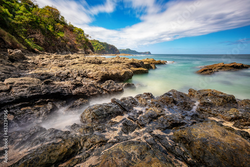 Long exposure, pacific ocean waves on rock in Playa Ocotal, El Coco Costa Rica. Famous snorkel beach. Picturesque paradise tropical landscape. Pura Vida concept, travel to exotic tropical country.