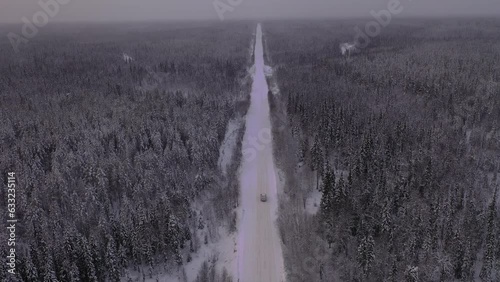 The car is moving on a snowy road. Landscape of winter taiga. Russian winter of northern latitudes from a drone.