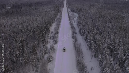 The car is moving on a snowy road. Landscape of winter taiga. Russian winter of northern latitudes from a drone.