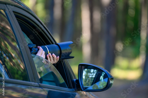 A private detective is sitting in the car, filming. The paparazzi sits in the car and photographs a famous person. Spy with a camera in the car.