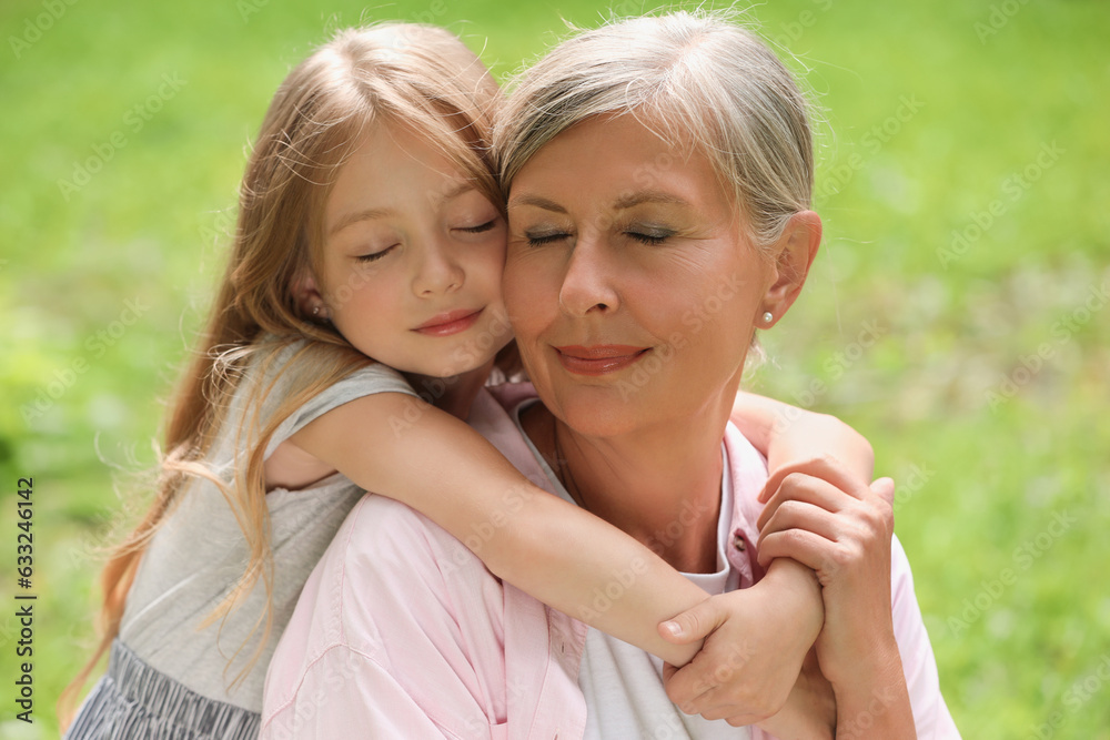 Happy grandmother hugging her granddaughter spending time together outdoors Happy grandmother hugging her granddaughter spending time together outdoors