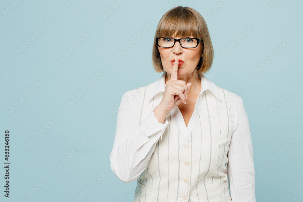 Employee business woman 50s wear white classic suit glasses formal clothes say hush be quiet with finger on lips shhh gesture isolated on plain pastel light blue background Achievement career concept Employee business woman 50s wear white classic suit glasses formal clothes say hush be quiet with finger on lips shhh gesture isolated on plain pastel light blue background Achievement career concept