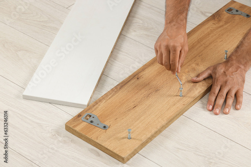 Man with hex key assembling furniture on floor, closeup