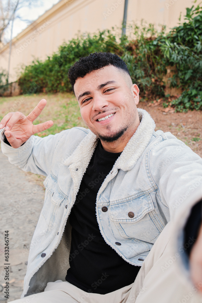 Vertical portrait of a young arab guy smiling taking a selfie looking ...