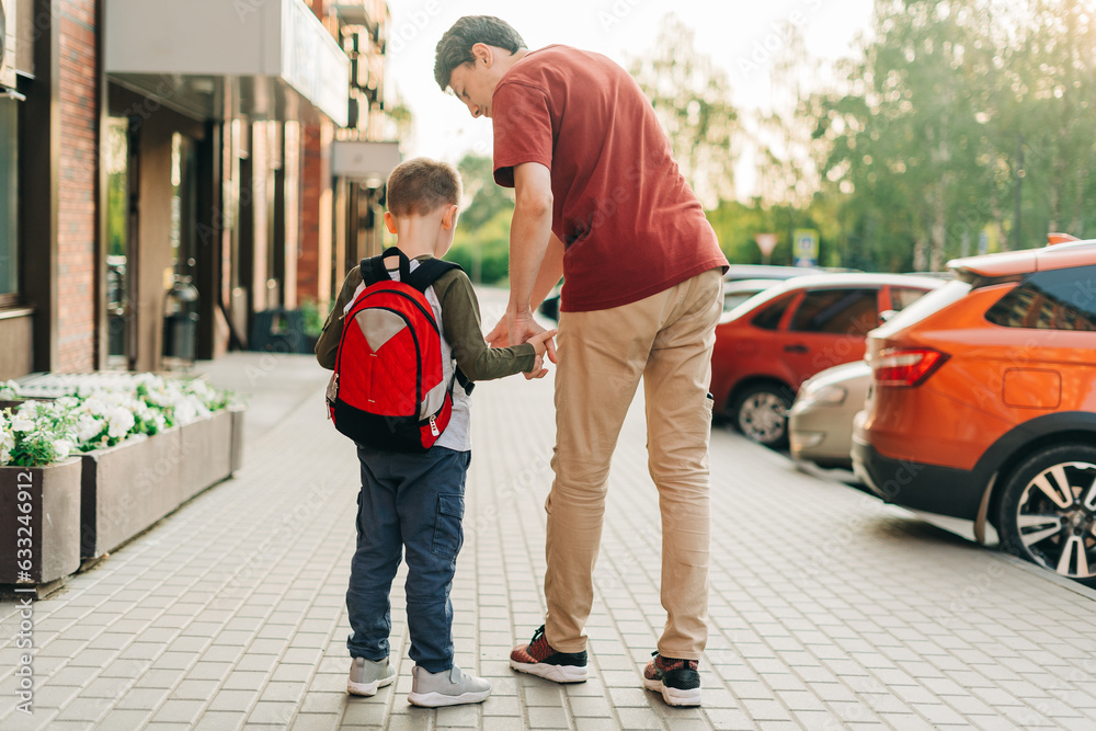 Happy father and kid son going to classes. Parent take child boy to school in first grade. Pupil of primary school go study with backpack outdoors in city street. Beginning of lessons. Back to school. Happy father and kid son going to classes. Parent take child boy to school in first grade. Pupil of primary school go study with backpack outdoors in city street. Beginning of lessons. Back to school.
