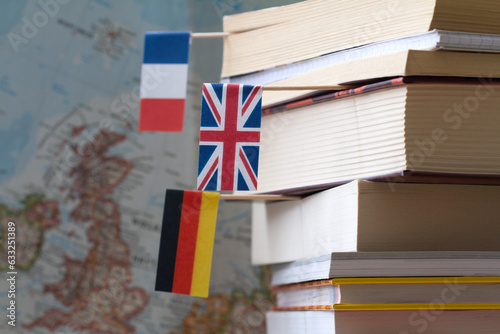 Stack of books with country flags on background of map, foreign language learning concept