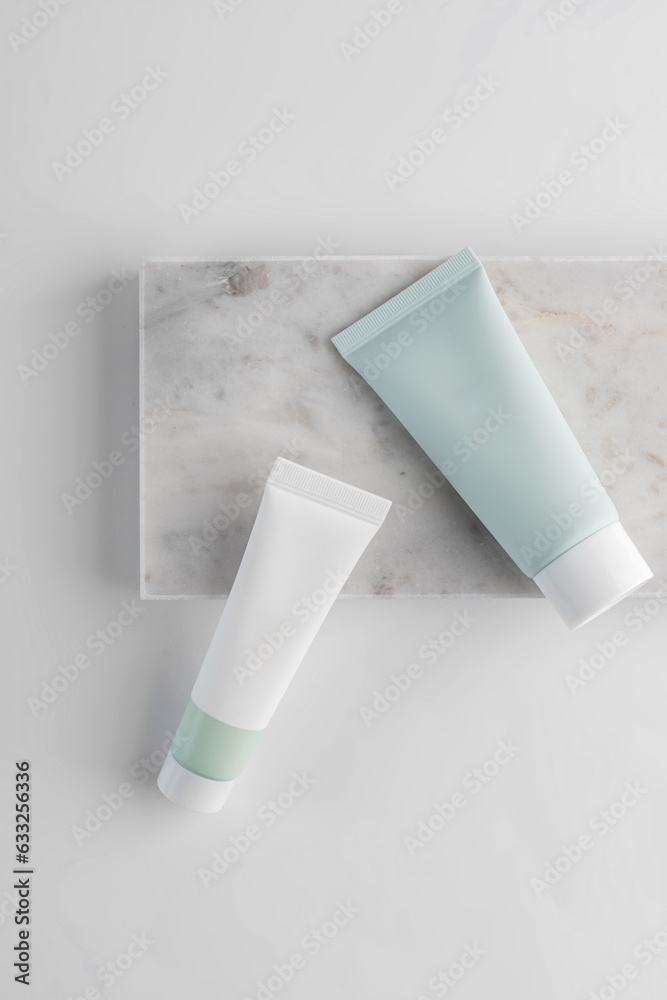 white and green cosmetic tubes on a white background on marble tray. The concept of a cream with natural ingredient and not testing on animals. white and green cosmetic tubes on a white background on marble tray. The concept of a cream with natural ingredient and not testing on animals.