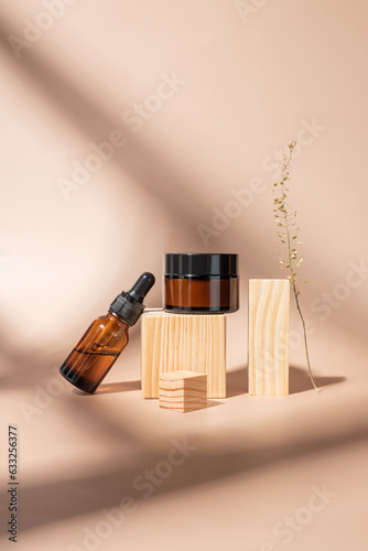 Set of cosmetic products in amber glass package. Beauty oil in droppper glass bottle and amber glass jar with day cream for healthy and young skin. Unbranded package for cosmetics promotion. photo