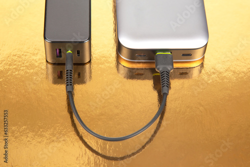 Power bank and charging plug with cable on a golden background. Electronic devices for charging gadgets