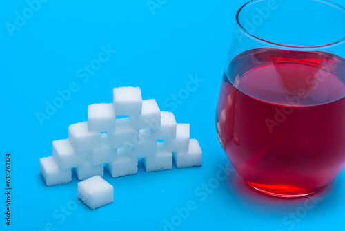 Zbliżenie na szklankę soku owocowego z dodatkiem niezdrowego białego cukru w kostkach 
