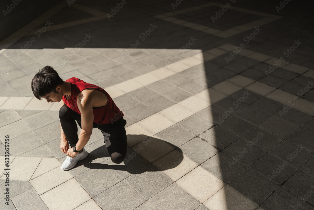 Preparation before jogging exercise. Young Asian man tying shoelace on her running shoes. Fitness and sport activity. Healthy exercise concept. Preparation before jogging exercise. Young Asian man tying shoelace on her running shoes. Fitness and sport activity. Healthy exercise concept.