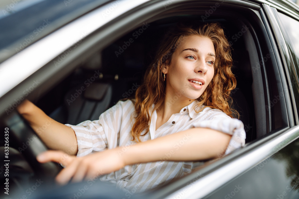 Beautiful smiling woman driving a car. The driver is a woman driving. Summer outdoor portrait. Car travel, lifestyle concept. Beautiful smiling woman driving a car. The driver is a woman driving. Summer outdoor portrait. Car travel, lifestyle concept.