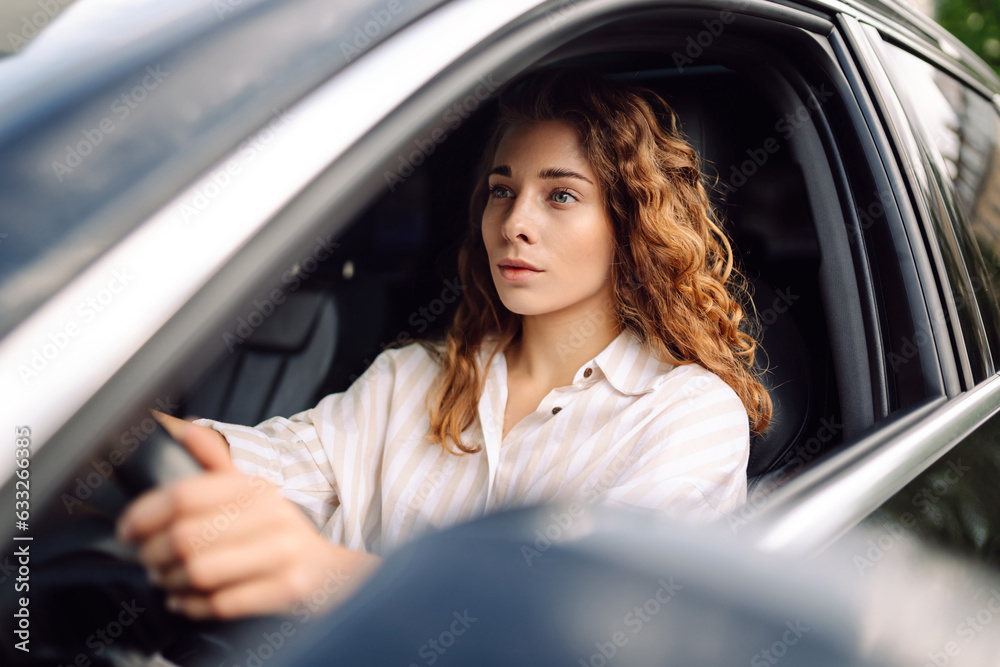 Beautiful smiling woman driving a car. The driver is a woman driving. Summer outdoor portrait. Car travel, lifestyle concept. Beautiful smiling woman driving a car. The driver is a woman driving. Summer outdoor portrait. Car travel, lifestyle concept.