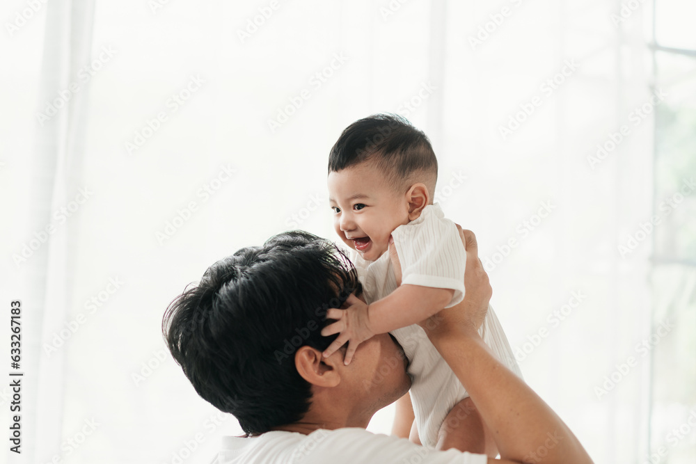 Happiness of fatherhood. Loving father spending time with infant child. Young Asian dad with adorable baby on his hands standing near window at home. Fathers day concept.. Happiness of fatherhood. Loving father spending time with infant child. Young Asian dad with adorable baby on his hands standing near window at home. Fathers day concept..