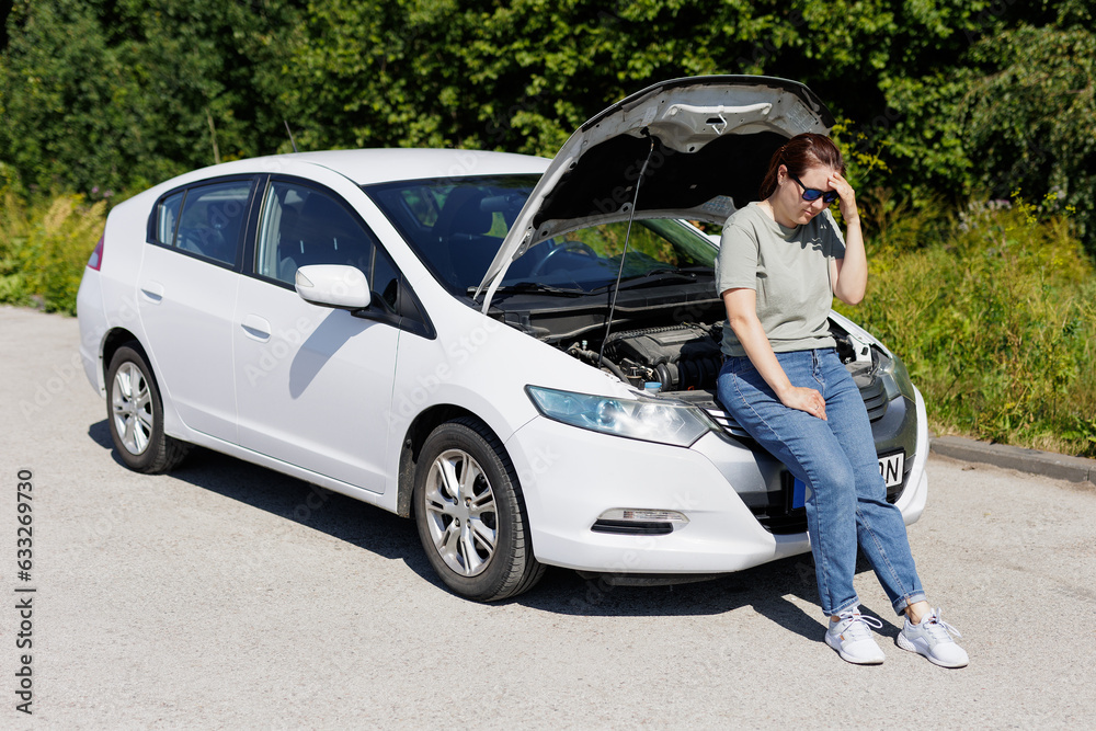 Sad woman sitting near opened hood. Trouble with car