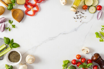 Frame of healthy food cooking ingredients background with fresh vegetables, herbs, spices and olive oil on marble table top view