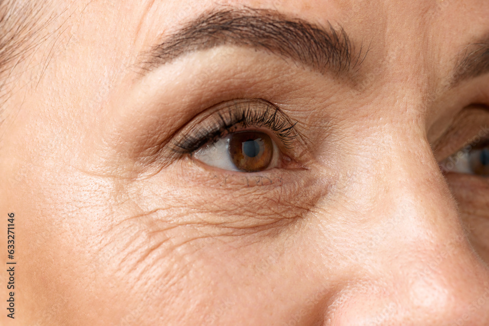 Obraz premium Closeup of middle aged woman eyes. Senior lady looking away, with well-kept and healthy skin. Mimic wrinkles.