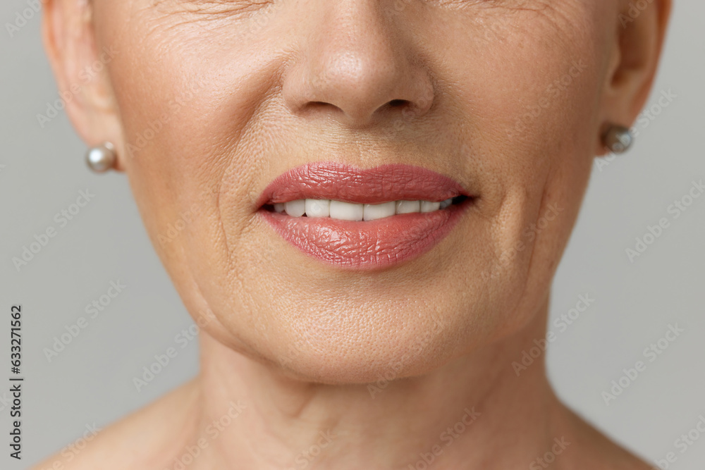 Obraz premium Cropped portrait of elderly smiling woman with copy-space over grey studio background. Dental health.