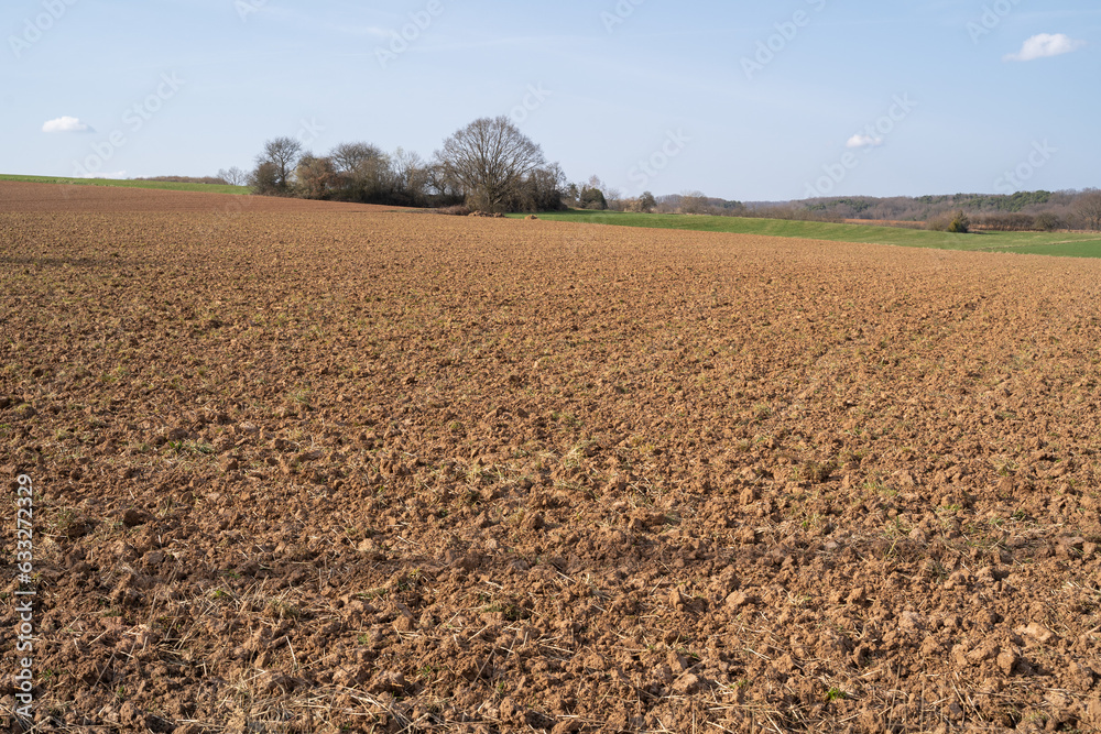 Plowed farmland with brown soil on a sunny day in spring Plowed farmland with brown soil on a sunny day in spring