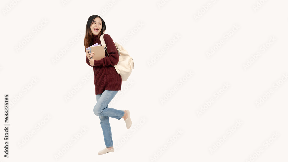 A pretty female college student stands against an isolated white background in a cute, joyful pose.