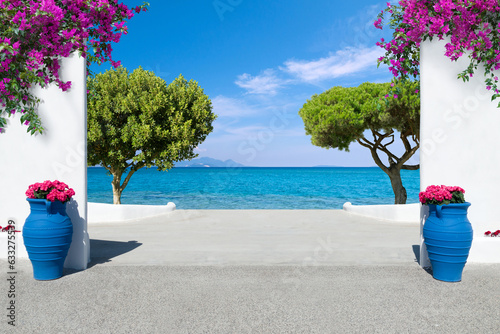 view to the mediterranean sea with white wall, potted blooming flowers, bougainvillea and trees in Greece