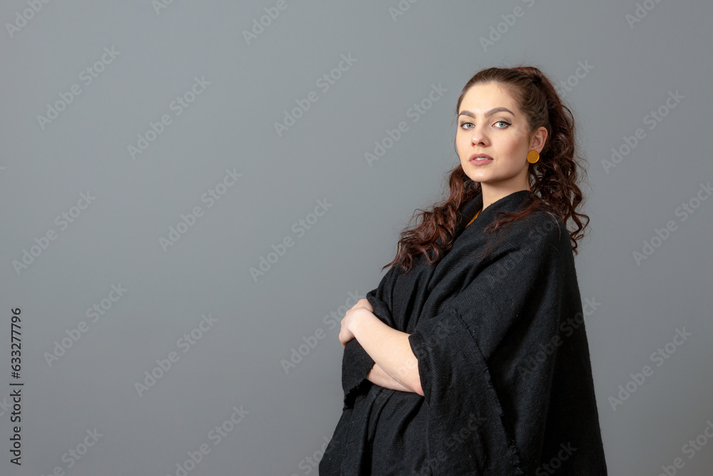 Naklejka premium portrait of charming curly-haired woman in a black cloak isolated on a gray background