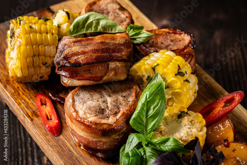 Fried meat medallions with corn, peaches and basil. Serving in a restaurant on a wooden board. place for text.