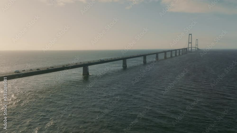 View of Denmark's coast as the sun sets over the Storebæltsbroen Bridge, showing the scenic roadway carrying traffic from coast to coast, and a stunning scenery of the ocean and coastline. View of Denmark's coast as the sun sets over the Storebæltsbroen Bridge, showing the scenic roadway carrying traffic from coast to coast, and a stunning scenery of the ocean and coastline.