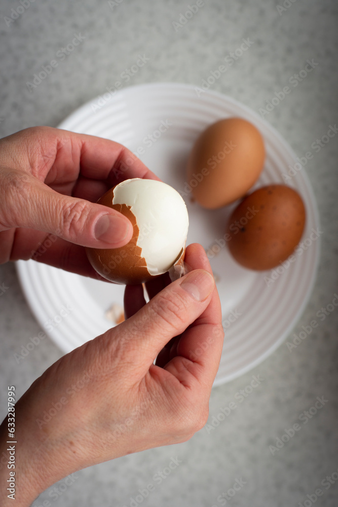 Caucasian female peeling hard boiled eggs closeup view from above