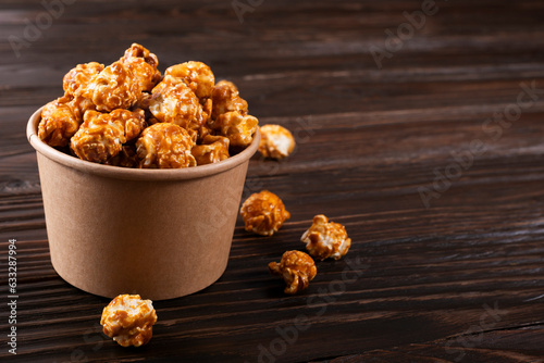 Obraz na płótnie Caramelized popcorn in paper bucket on wooden kitchen table w salonie