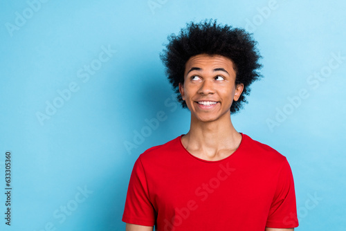 Photo of funny multinational wavy hairdo guy smiling looking empty space wear red t-shirt isolated blue pastel color background