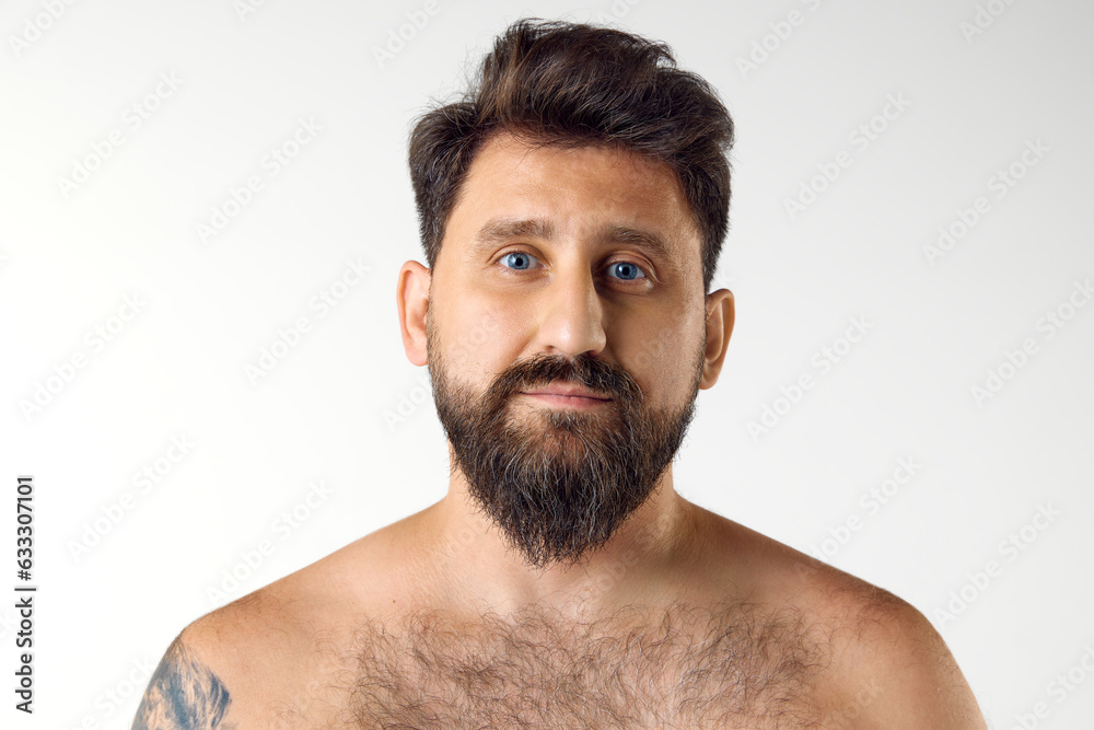 Portrait of handsome bearded mature man with blue eyes posing shirtless against white studio background. Spa. Concept of men's beauty, skin care, cosmetology, health and wellness. Copy space for ad Portrait of handsome bearded mature man with blue eyes posing shirtless against white studio background. Spa. Concept of men's beauty, skin care, cosmetology, health and wellness. Copy space for ad