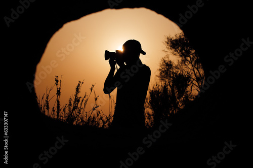 Photographer taking a nature photo during sunset. Picture taken from the hole of a cave.
 photo