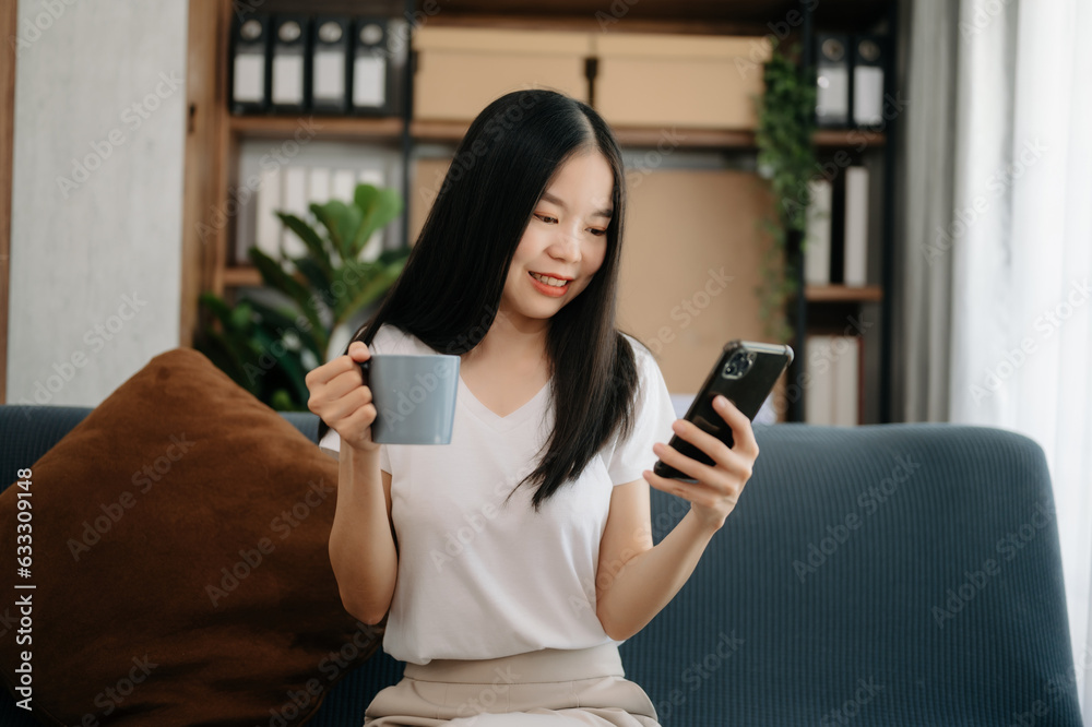 Young Asian woman using the smartphone and tablet on the sofa at home. Young Asian woman using the smartphone and tablet on the sofa at home.
