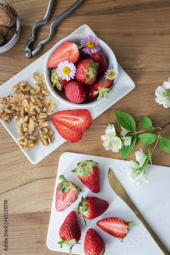 Strawberries with walnuts and flowers on a wooden background. Healthy snack