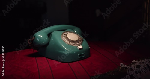 The camera is slowly moving away from the dial phone placed on the table in the retro interior. The dramatic atmosphere of an unknown call photo